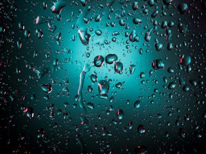 Water droplets on a teal-lit surface