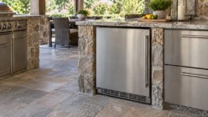 An outdoor refrigerator in a covered patio kitchen with a stone counter