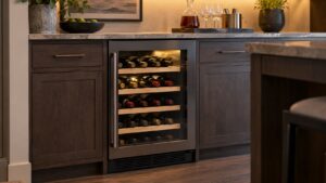 A built-in wine cooler with a glass door showing rows of bottles in a softly lit home bar